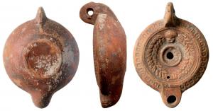 LMP-41595 - Lampe galette : masque, couronne, M NOV IVSTI
terre cuite
TPQ : 120 - TAQ : 180
Lampe moulée, anse verticale percée à deux sillons sur la tranche. Réservoir circulaire à profil biconvexe asymétrique. Bandeau penché vers l'extérieur décoré d'une couronne d'oves. Disque en cuvette limitée par deux sillons concentriques. Décor : masque de théâtre couronne de laurier, bourrelet central. Trou d'évent. Bec arrondi limité par un trait droit. Base circulaire plate en léger relief limitée par un sillon estampillée en creux M NOV IVSTI. Engobe rouge brique sur toute la lampe.