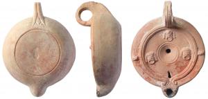 LMP-41596 - Lampe galette à tenons : planta pedis, masques comédie
terre cuite
TPQ : 75 - TAQ : 150
Lampe moulée, anse verticale percée à trois sillons sur la tranche, un alpha gravé en dessous. Réservoir circulaire à profil convexe. Bandeau penché vers l'extérieur, deux tenons rectangulaires sur l'axe horizontal. Disque plate limitée par deux bourrelets concentriques se terminant en volute sur le bec. Décor : trois masques de comédie. Petite cuvette centrale à deux sillons. Petit bec arrondi. Traces de combustion. Base circulaire plate en léger relief limitée par un sillon. Planta pedis en creux. Type engobé en rouge.