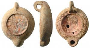 LMP-41610 - Lampe à bec cordiforme : Buste d'Hygie
terre cuite
TPQ : 225 - TAQ : 250
Lampe moulée, anse verticale percée à deux sillons sur la tranche. Réservoir circulaire à profil biconvexe. Bandeau penché vers l'extérieur au décor de guirlande de laurier noué. Disque en simple cuvette limitée par deux sillons ; serpent et  buste d'Higie à gauche.  Bec arrondi cordiforme. Base circulaire plate en léger relief limitée par un bourrelet et deux sillons. Porte un petit cercle au centre et un décor de traits rayonnants. Restes d'engobe rouge sur toute la lampe.