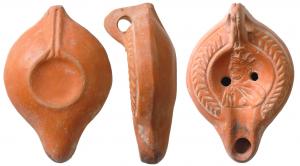 LMP-41662 - Lampe Hayes I : Buste couronné
terre cuite
TPQ : 250 - TAQ : 350
Lampe moulée, anse verticale percée à un sillon, faisant avec la patère une excroissance caractéristique du type. Réservoir piriforme de profil biconvexe. Palmes descendantes sur le bandeau. Bec moyen et  disque entourés par un bourrelet : buste barbu à gauche, couronne radiée. Base plate limitée par un bourrelet; double bourrelet rejoignant l'anse, l'ensemble formant une patère. Engobe rouge orangé brillant.