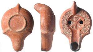 LMP-41679 - Lampe chrétienne à canal, à bec épaulé, chrisme
terre cuite
TPQ : 350 - TAQ : 600
Lampe moulée, à anse pleine. Réservoir piriforme de profil biconvexe. Décor de  fleurons  (Bussière Q10) sur le bandeau plat. Disque  limité par un sillon, chrisme perlé, bouclé à droite. Bec long à canal ouvert sur le disque, épaulé. Deux excroissances au départ, sur le bord du réservoir. Base circulaire limitée par un bourrelet. Trois bourrelets la relie à l'anse et au départ du bec. Engobe rouge brique.