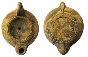 LMP-41988 - Lampe à bec rond limité par un trait : C POMPO
terre cuite
TPQ : 80 - TAQ : 140
Lampe moulée, anse verticale percée à deux sillons sur la tranche. Réservoir circulaire à profil biconvexe. Bandeau penché vers l'extérieur, disque en cuvette limitée par deux sillons concentriques. Trou d'évent. Bec arrondi limité par un trait droit. Base circulaire plate en léger relief limitée par deux sillons. Estampée C POMPO  surmontant deux petits cercles concentriques en creux.  Engobe rouge marron sur toute la lampe.