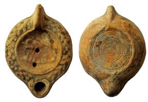 LMP-41994 - Lampe à bec cordiforme : Cheval
terre cuite
TPQ : 150 - TAQ : 250
Lampe moulée, anse verticale forée à un sillon sur la tranche; bord légèrement incliné vers l'extérieur et orné d'une guirlande; médaillon  représentant un cheval à gauche, la tête penchée er retournée vers le poitrail;  bec cordiforme; base circulaire limitée par un bourrelet, orné de cercles concentriques. Argile beige orangé, engobe brun.