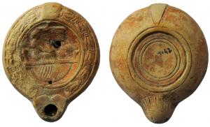 LMP-41998 - Lampe à bec cordiforme : Scène érotiqueterre cuiteTPQ : 200 - TAQ : 250Lampe moulée, anse verticale percée à deux sillons sur la tranche. Réservoir circulaire à profil biconvexe. Bandeau penché vers l'extérieur orné d'une couronne de laurier noué. Disque en  cuvette limitée par deux sillons. Décor : scène érotique avec deux personnages sur un lit (l'homme tient relevées les jambes repliées de la femme couchée devant lui sur le dos]. Bec arrondi cordiforme; bande de stries au revers. Base circulaire plate  limitée par un  anneau en relief, cercles concentriques incisés. Restes d'engobe rouge sur toute la lampe.