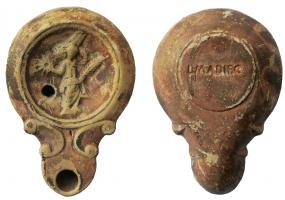 LMP-42005 - Lampe bec a volutes doubles : Victoire, L M ADIEC
terre cuite
TPQ : 90 - TAQ : 140
Moulée, sans anse. Réservoir circulaire de profil convexe. Bandeau étroit penché vers l'extérieur. Disque en cuvette limitée par deux cercles en creux. Décor : Victoire de face, tenant palme et couronne. Bec long arrondi, flanqué de deux volutes doubles se poursuivant sous le bec; trou d'évent. Base plate limitée par un sillon, estampillée en creux L M ADIEC. Engobe brun sur toute la lampe.