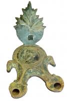 LMP-42057 - Lampe à deux becs et têtes de chevaux, vernis plombifère
terre cuite
TPQ : 50 - TAQ : 150
Lampe à deux becs en ogive, deux têtes de chevaux en guise de tenons sur les côtés; le disque concave, cerné de moulures, peut être lisse ou orné d'un motif radiant, ou figuré; réflecteur de forme variable, toujours orné au moule : triangulaire (palmette), ou en forme de feuille souvent très découpée (vigne).