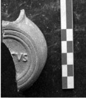 LMP-42188 - Lampe de firme : FESTVS
terre cuite
TPQ : 50 - TAQ : 200
Lampe moulée sans anse: le réservoir circulaire est de profil biconvexe asymétrique; bandeau penché vers l'extérieur portant deux tenons rectangulaires non percés, sur l'axe horizontal. Disque creux, plat et peu profond, bordé par un bourrelet continu. Bec long au petit canal non communiquant avec le disque, chanfeiné sur les côtés. Base circulaire plate en creux limitée par deux anneaux concentriques enfermant l'estampille moulée FESTVS en relief. Pâte orange brique, sans engobe.