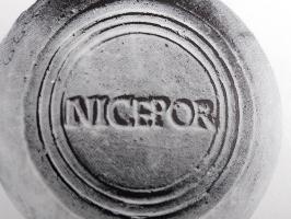 LMP-42445 - Lampe de firme : NICEPOR
terre cuite
TPQ : 100 - TAQ : 150
Lampe moulée sans anse: le réservoir circulaire est de profil biconvexe asymétrique; bandeau penché vers l'extérieur portant deux ou trois tenons rectangulaires non percés, sur l'axe horizontal. Disque en cuvette profonde bordée par un bourrelet continu. Bec long au petit canal non communiquant avec le disque, chanfeiné sur les côtés. Base circulaire plate en creux limitée par deux anneaux concentriques enfermant l'estampille moulée NICEPOR en relief. Engobe rouge brique peu adhérent.