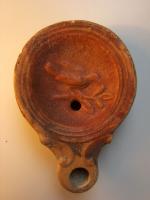 LMP-4312 - Lampe Loeschcke IV : Oiseau sur branche 
terre cuite
TPQ : 50 - TAQ : 150
Lampe à bec à ogive et volutes latérales; disque orné d'un oiseau sur branche. Argile noisette, engobe orange foncé à marron foncé; base plate entourée d'un anneau en relief.