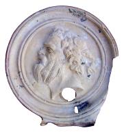 LMP-4386 - Lampe Loeschcke IV : Silène
terre cuite
TPQ : 120 - TAQ : 250
Lampe à bec à volutes (fragment); disque orné d'une tête de silène. Argile beige, engobe orange clair.