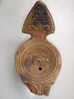 LMP-4460 - Lampe Loeschcke IV : Lièvre
terre cuite
TPQ : 50 - TAQ : 150
Lampe à long bec à ogive et volutes internes. Disque décoré d'un lièvre. Argile noisette, engobe marron; base plate. Anse à réflecteur triangulaire avec palmette.