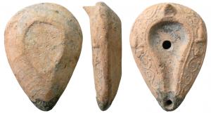 LMP-5009 - Lampe en forme d'amandeterre cuiteTPQ : 400 - TAQ : 700Anse en simple tenon conique. Réservoir en forme d'amande à canal et de profil biconique. Disque sans décor entouré par un sillon et percé d'un petit trou d'alimentation. Il est ouvert sur le canal de même niveau. Bec arrondi non saillant. Traces de combustion. Décor de rinceaux habités par deux colombes sur l'axe horizontal  en relief sur le bandeau.
Base plate  limitée par un bourrelet ovale..