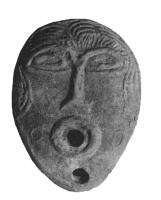 LMP-5051 - Lampe en forme d'amande, visageterre cuiteTPQ : 600 - TAQ : 700Lampe en forme d'amande, sans anse, dont la forme générale et le décor reproduisent un visage féminin (?), aux yeux en amande, le nez allongé et la bouche indiquée par le trou de remplissage; petits cercles en relief sur les joues. Argile brun-rouge, pas d'engobe.