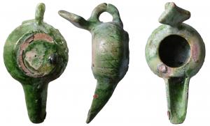 LMP-6002 - Lampe islamique émailléeterre cuiteTPQ : 1000 - TAQ : 1300Tournée modelée. Anse en boudin rapportée, relie le milieu du réservoir à une anse réflecteur en losange.  Réservoir circulaire, de profil globulaire. Bandeau sans décor autour d'un grand trou dalimentation. Décor de croisillons gravés sur le pourtour du réservoir. Long bec ouvert rapporté. Base circulaire plate. Email vert sur toute la lampe.