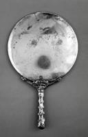 MRR-4058 - Miroir Lloyd-Morgan Group J : circulaire à manche en forme de massue
argent
Miroir circulaire légèrement bombé, forte moulure périphérique au revers; le manche coulé et rapporté, certainement fixé par brasure, figure une massue d'Hercule avec, au sommet, une léontè.