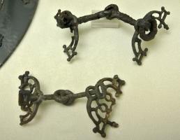 MRS-2016 - Mors brisé
fer, bronze
Mors de filet dont les deux éléments, articulés au centre par deux boucles perpendiculaires, se terminent à l'opposé par des bélières rectangulaires ; appliques latérales semi-circulaires à décor filiforme (