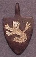 PDH-7002 - Pendant en forme d'écu armoriébronzeTPQ : 1250 - TAQ : 1500Pendant en forme d'écu armorié, suspension sommitale ; les armes peuvent être émaillées et le fond souvent doré.