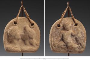 PSN-3002 - Peson semi-circulaire moulé
terre cuite
peson moulé, en forme de fer à cheval, base droite, deux trous de supsnesion au sommet; les deux faces portent un motif moulé, en fort relief : d'un côté, deux bustes d'amants s'embrassant (Apollon et  Artémis ?), de l'autre, Eros jouant avec une oie.