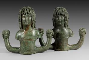 SCH-4008 - Suspension de caisse de char : Barbare
bronze
Suspension de caisse de char constituée d'une douille surmontée d'un buste humain, coupé au niveau des bras, émergeant d'un fleuron simplifé et figurant un jeune barbare, le visage aux traits sereins encadrés d'une lourde chevelure en mèches rectilignes; de part et d'autre de la douille centrale, robustes crochets surmontés d'une tête de même style.