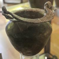 SIT-3033 - Situle stamnoïde
plomb
Situle stamnoïde, à col étranglé et lèvre déversée; les attaches d'anses consistent en deux gros anneaux coulés sur le bord du vase en même temps que lui; anse plate et coulée, épaisse, avec un anneau de suspension centré.