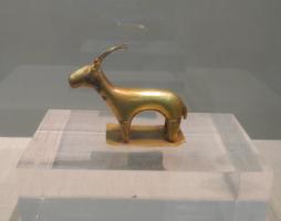 STE-1009 - Statuette zoomorphe : capriné / antilopidé
or
Figurine de capriné / antilopidé au corps assez massif dotée de longues cornes légèrement courbées en arrière, posée sur une fine plaque.