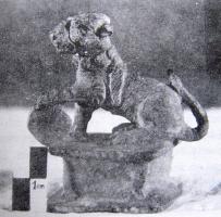 ACH-4002 - Applique de charbronzeFigurine plastique sur socle quadrangulaire, ouvert à l'arrière et par-dessous : lion assis, posant la patte antérieure gauche sur un disque.
