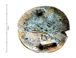 APH-4169 - Applique de harnaisbronzeApplique circulaire lisse, formant un disque légèrement bombé; au revers, un bouton en T et, diamétralement opposé, une bélière rectangulaire plate pour le passage d'une sangle.