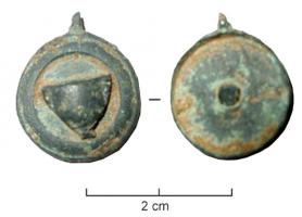 BTS-4161 - Boîte à sceau circulaire : canthare ?bronzeBoîte à sceau circulaire dont le couvercle, pourvu d'une moulure circulaire, est orné d'un ornement riveté en forme de canthare ou de skyphos (à moins qu'il ne s'agisse d'une tête de dauphin) ; fond percé de 4 trous dont un central.