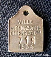 FIS-9003 - Plaque fiscale pour chien : Saint-NazairebronzePlaque rectangulaire surmontée d'une bélière, avec une inscription moulée : VILLE DE SAINT-NAZAIRE / CHIENS 2E CRIE / 1934  et au-dessus de la date, un numéro estampé.