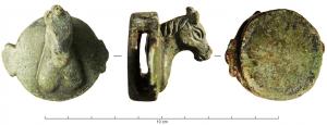 JHA-4032 - Passant de harnaisbronzePassant en forme de boîtier cylindrique, avec dans l'épaisseur le passage pour une sangle horizontale; la face externe s'orne d'une tête de cheval en haut relief, entre deux ornements latéraux foliacés.