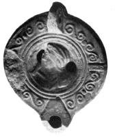 LMP-4058 - Lampe Loeschcke VIII : Busteterre cuiteTPQ : 400 - TAQ : 500Lampe à bec rond; disque décoré d'un buste à gauche (personnage [divin?] avec canne-marteau); anse percée; épaule ornée d'esses et d'ergots.