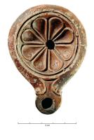 LMP-42720 - Lampe Loeschcke V : rosace à huit pétalesterre cuiteTPQ : 50 - TAQ : 150Lampe à bec en ogive et volutes simples, médaillon orné d'une rosace à huit pétales ; dans les trois pétales situés près du bec, inscription en creux avec lettres formées de traits et de points : L.A.I. (à lire le bec en haut)