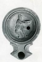 LMP-42745 - Lampe Loeschcke I : Ulysse tendant une coupeterre cuiteTPQ : 40 - TAQ : 80Lampe moulée, avec large bec à volutes et grand médaillon rond montrant Ulysse portant une tunique courte et tenant un canthare.