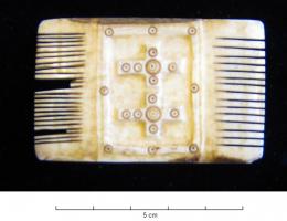 PGN-5001 - Peigne orné à deux rangées de dentsos ou ivoirePeigne plat, à deux rangées de dents de largeurs différentes, dont la partie centrale s'orne de deux croix juxtaposées, ornées de cercles oculés.