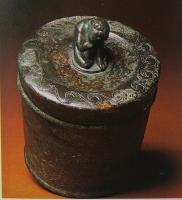 PYX-3001 - PyxidebronzePyxide à corps cylindrique, couvercle débordant également cylindrique, avec une bordure gravée et une figurine centrale faisant office de préhension.