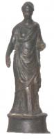STE-4153 - Statuette : femmebronzeStatuette en bronze présentant une femme debout vétue d'un ample chiton, couvrant le corps jusqu'aux pieds, à l'exception, de l'épaule droite sur laquelle apparait une tunique. La main droite pendante, tient un objet indéterminé, tandis que le bras gauche se tient horizontalement. Socle tronconique avec une moulure en bas et une en haut.