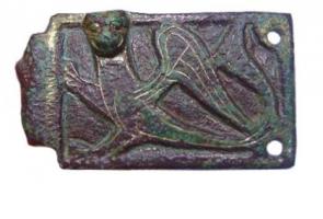 BAC-6018 - Boucle à chape émailléebronzeBoucle à chape rectangulaire, à deux rivets de fixation; motif en léger relief et doré : dragon ailé à gauche, tête de face (rapportée ...?).