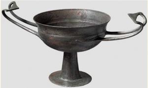 CAN-3001 - CantharebronzeVase à boire à panse profonde, carène et lèvre en bandeau déversée vers l'extérieur;  pied haut,sur base circulaire; paire d'anses fines et redressées vers le haut, repliées en forme de crosse et dépassant le bord du vase.