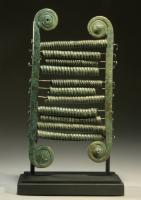 CHF-1001 - ChalcophonebronzeTPQ : -800 - TAQ : -500Instrument de musique composé de deux barres verticales terminées par des spirales, reliées par des axes (peut-être en bois) sur lesquels jouent librement des tubes formés à partir de ressorts compacts.
