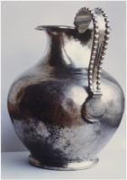 CRU-4032 - CrucheargentCruche martelée, à panse renflée, col cylindrique et lèvre évasée à bec tréflé, pied annulaire ; l'anse surélevée, en ruban bordé de grosses perles, se termine par une attache ronde et lisse.