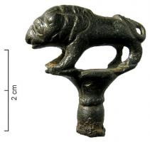 EPG-4433 - Épingle à tête en forme de lionbronzeEpingle dont le sommet, mouluré, s'élargit pour former un chapiteau sur lequel se tient une figurine de lion, solidement campée sur des pattes; la queue retournée bat les flancs.