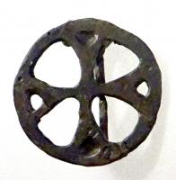FIB-41634 - Fibule en forme de croix inscritebronzeTPQ : 400 - TAQ : 500Fibule en forme de croix à branches plates, légèrement évasées vers l'extérieur et parfois ajourées à leurs extrémités, inscrite dans un cercle; au revers, articulation à charnière entre deux plaquettes coulées.