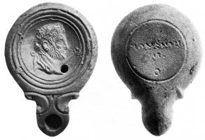 LMP-4026 - Lampe Loeschcke IV : Empereur, ROMANIIS IS Oterre cuiteLampe à bec en ogive, doubles volutes; bandeau mouluré (Sch. xxxx); médaillon orné d'un buste à droite, barbu et diadémé, la massue sur l'épaule (Hadrien en Hercule); devant, sceptre fleuri. Marque en creux ROMANIIS / IS/ O.