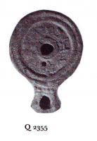 LMP-41047 - Lampe ronde à bec allongé : Texte Palmyrénienterre cuiteLampe ronde à bec allongé. Epaule décorée d'une inscription en palmyrénien dédiée à Abigbol et Malakbêl.