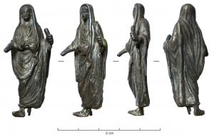 STE-4054 - Statuette : prêtreargentPrêtre officiant, caractérisé par sa toge dont un bord vient recouvrir la tête; la main droite effectue une offrande, la gauche peut tenir divers objets (souvent, un coffret de boules d'encens).