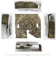 SER-4004 - Serrure à rotationbronzeBoîtier quadrangulaire, souvent presque carré, formé par le repli que les quadtre côtés d'une feuille de tôle découpée, ornée sur la face supérieure de cercles concentriques et percée de plusieurs ouvertures : une centrée pour la clé à rotation ; une ou deux rectangulaires, pour le ou les moraillons, disposées sur les côtés ou dans l'alignement de l'entrée de la clé.
