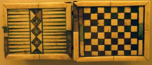 TAJ-7001 - Plateau de jeu ou tablieros ou ivoirePlateau portatif et pliant, en bois plaqué d'ivoire blanc et teinté. Chacun des deux couvercles de la boîte, reliés par une charnière, correspond à un jeu : trictrac 