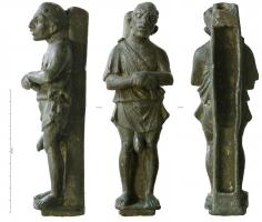 ACH-4011 - Applique de charbronzeApplique en forme de figurine sur un socle ouvert par dessous et souvent à l'arrière, où un pilier lisse sert de fond mais assure également la fixation du décor sur un montant vertical : personnage grotesque (esclave en tunique), ithyphallique, les mains jointes sur le ventre, la tête penchée sur le côté, les traits épais.