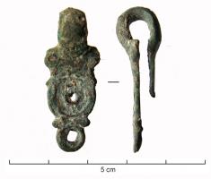 AGH-4006 - Agrafe de harnaisbronzeAgrafe de harnais dont la plaque antérieure est ornée de deux gros cercles concentriques de diamètre décroissant, avec rivet central, encadrés de petits cercles oculés.