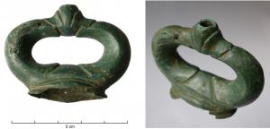 AJG-3003 - Anneau de jougbronzeTPQ : -100 - TAQ : 1Anneau de joug en fonte creuse, à décor plastique, comportant un anneau réniforme posé sur une base ; au sommet, motif central accosté de moulures, creux par-dessus (pour un décor incrusté? émaillé ?)